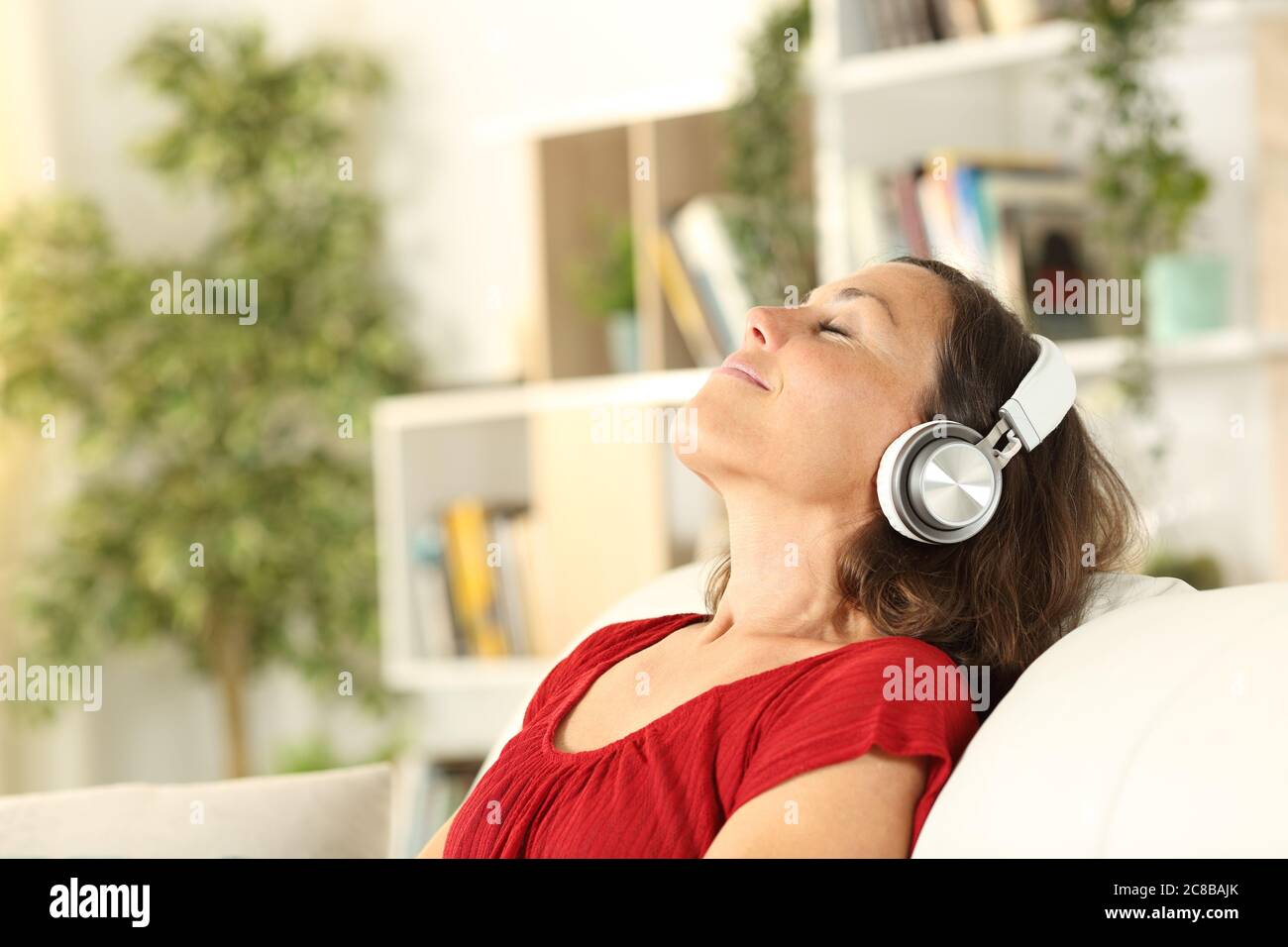 Entspannte Erwachsene Frau hört Musik mit Kopfhörern im Bus zu Hause Stockfoto