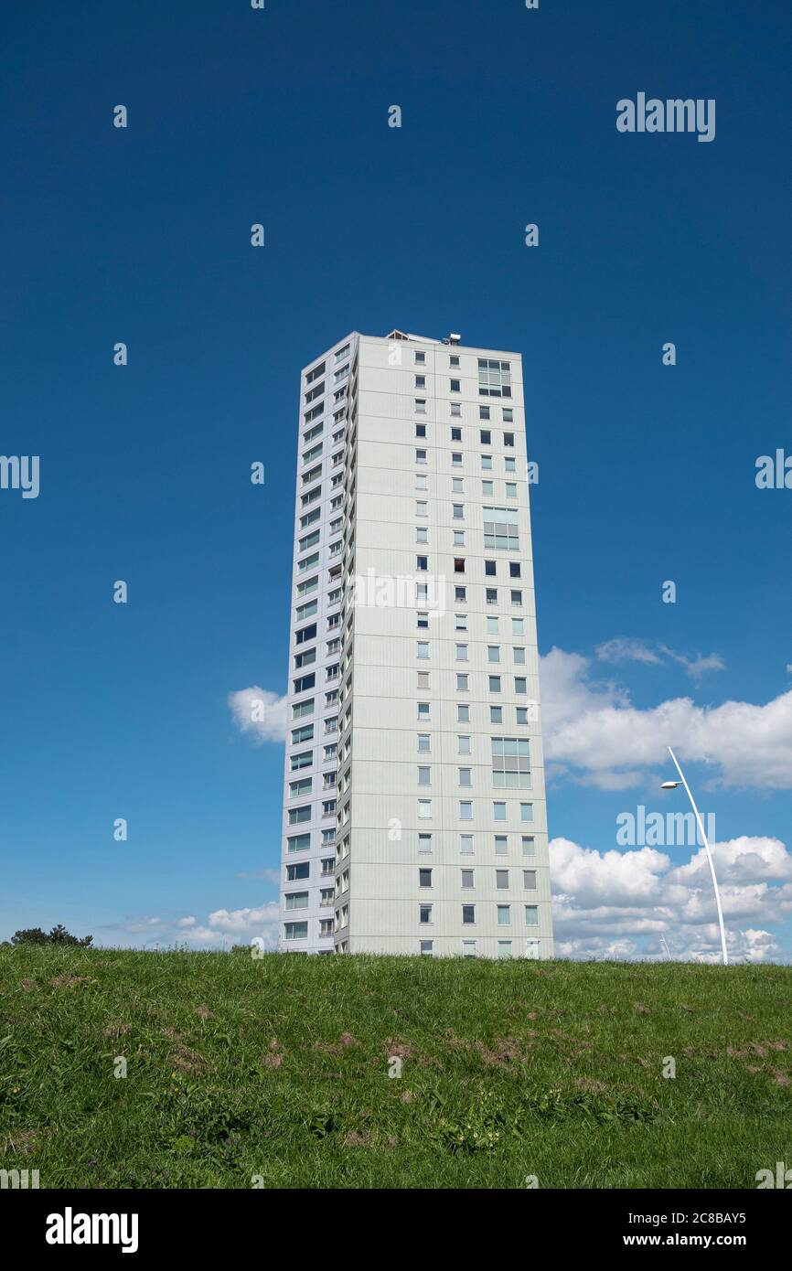 Terneuzen, Niederlande, 12. Juli 2020, großes weißes Appartementhaus auf einem grünen Hügel mit blauem Himmel und Wolken Stockfoto