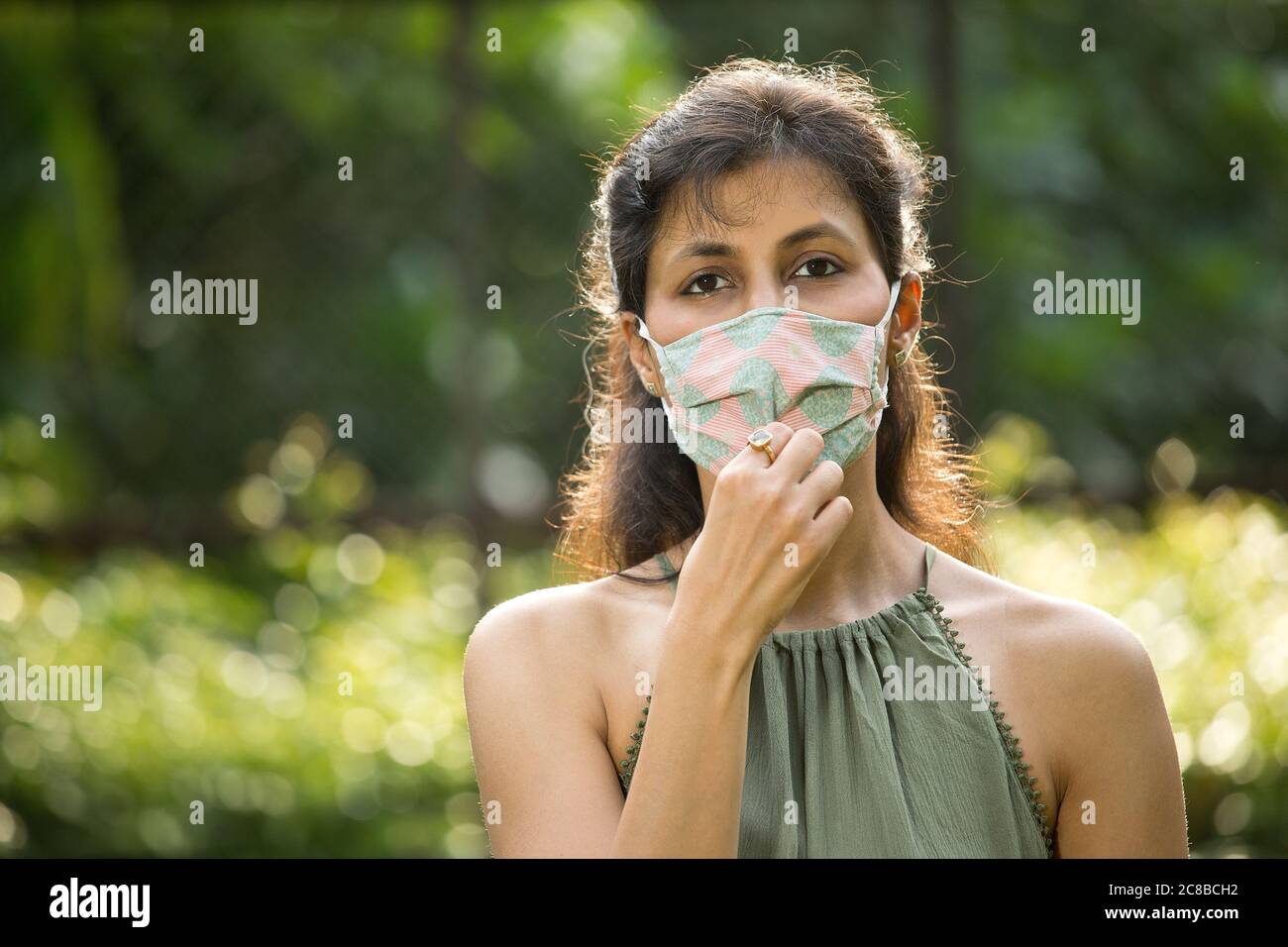 Frau Einstellung schützende Gesichtsmaske im Park Stockfoto