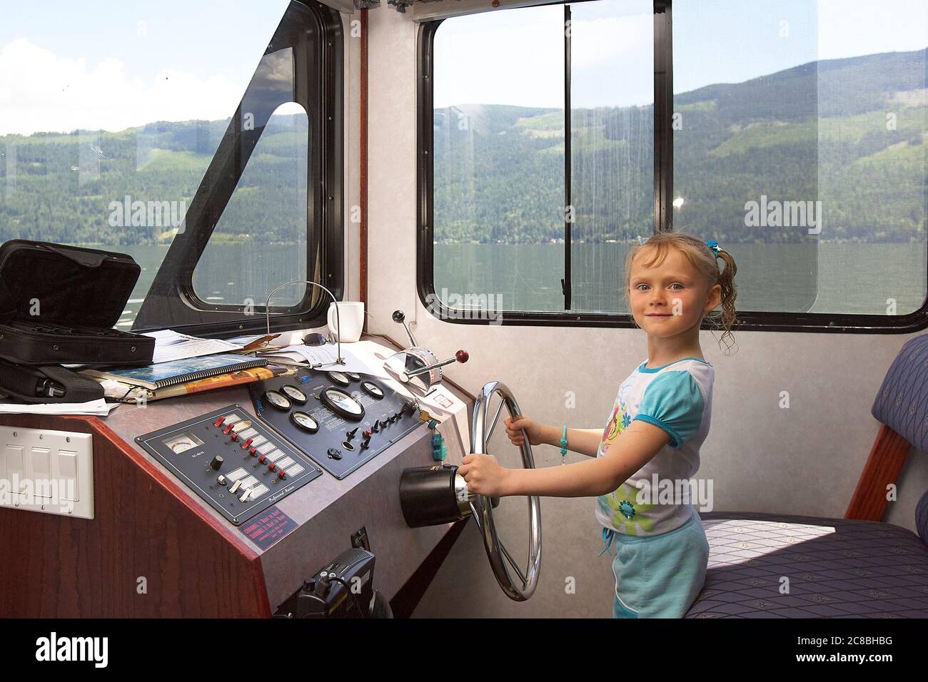 Junges Mädchen am Steuer, das ein großes Hausboot fährt. Stockfoto