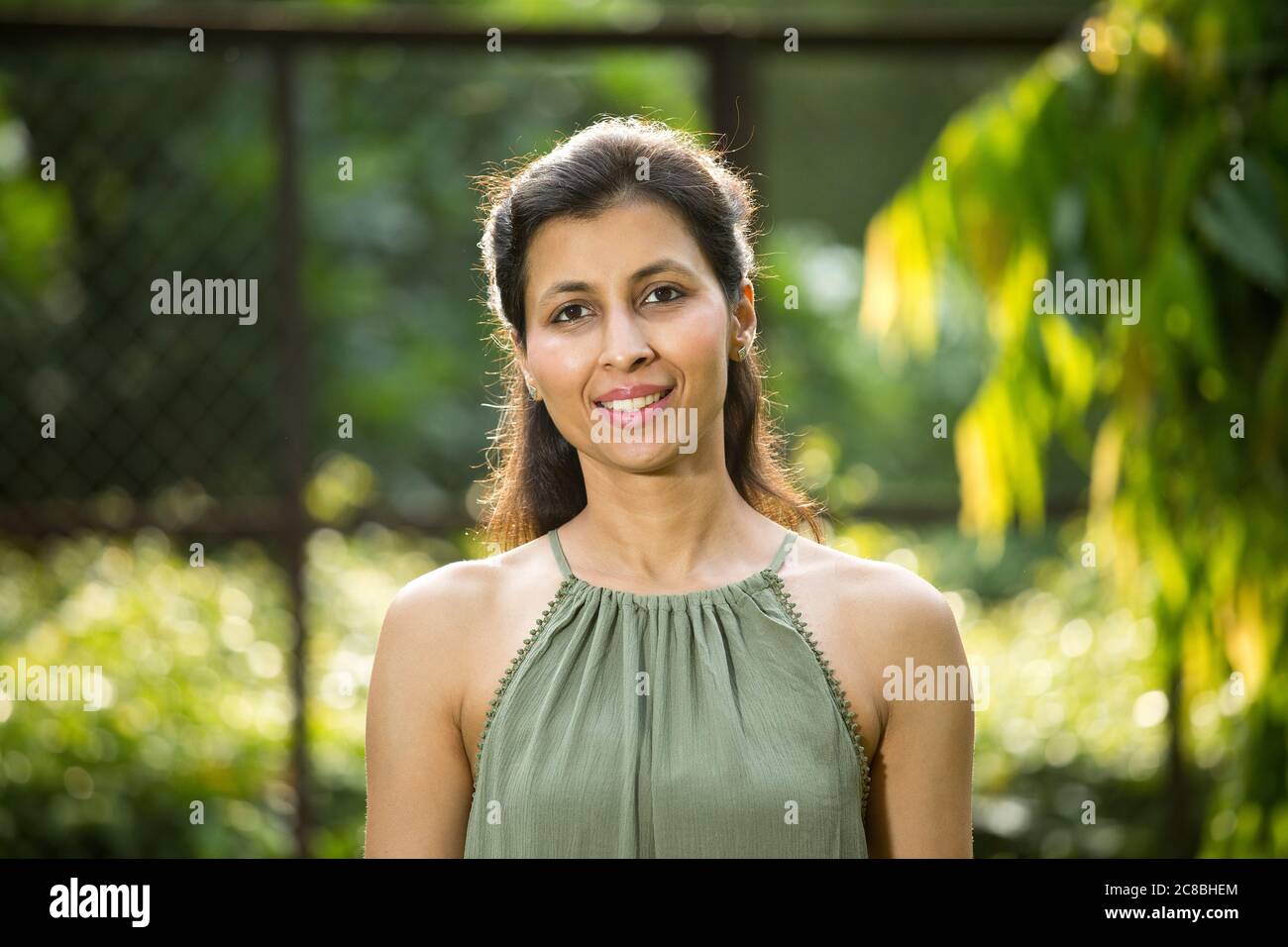 Porträt einer glücklichen Frau im Park, die die Kamera anschaut Stockfoto