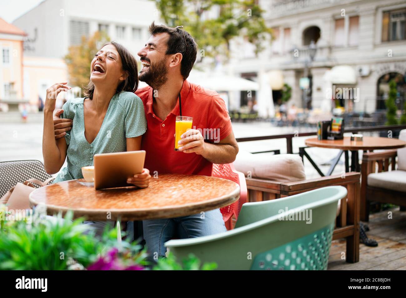 Ein Paar, das digitale Tablets verwendet, lächelt und spricht im Café Stockfoto