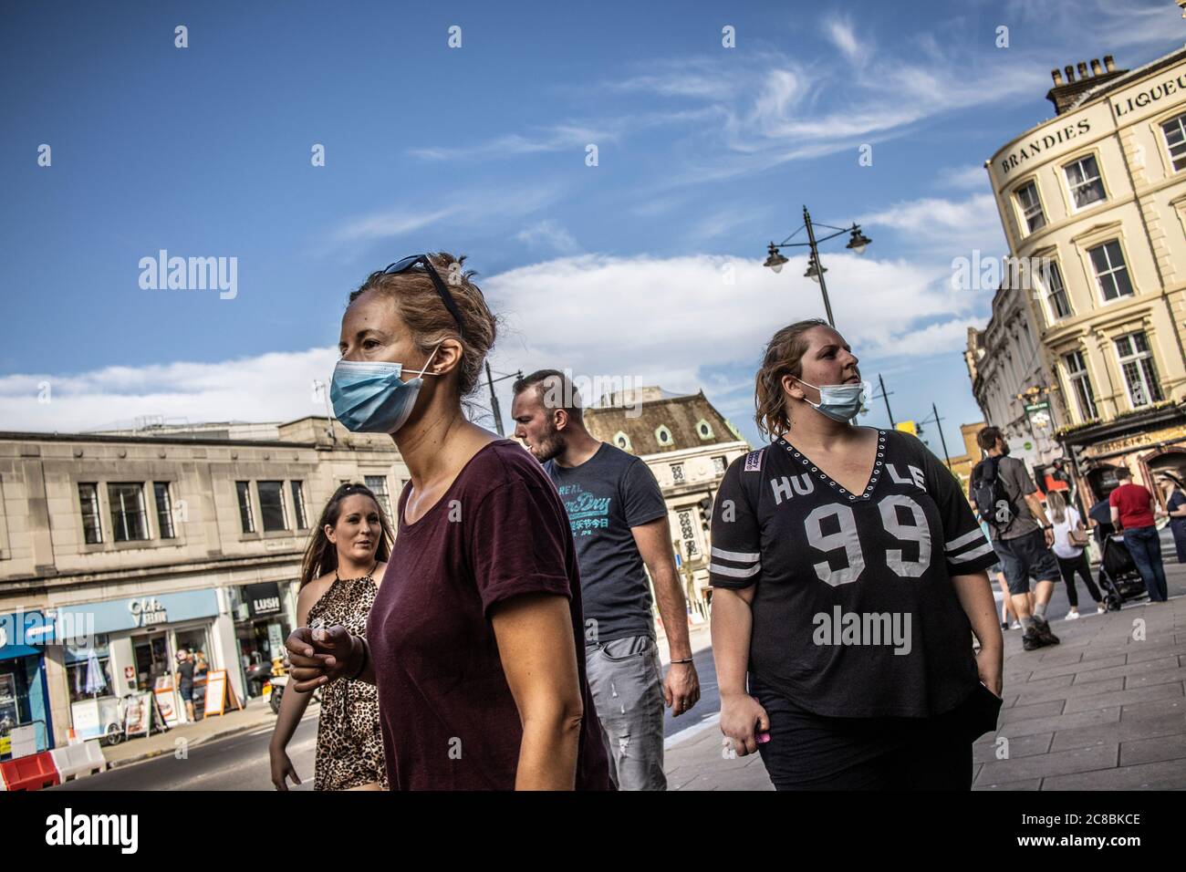 Fußgänger tragen Gesichtsmasken im Zentrum von Wimbledon Stadt, London SW19, nachdem die Coronavirus Beschränkungen wurden langsam aufgehoben Geschäfte wieder zu öffnen. Stockfoto