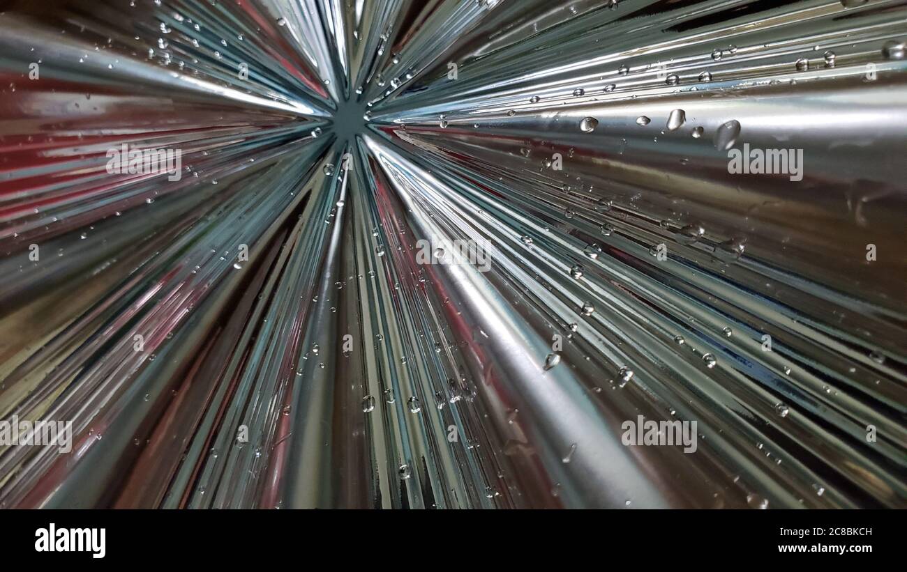Verschwommener abstrakter Hintergrund von glänzenden Strahlen und klaren flüssigen Tropfen. Defokussierung Zentrum der sternförmigen Zusammensetzung durch metallische Oberflächenlinien Stockfoto