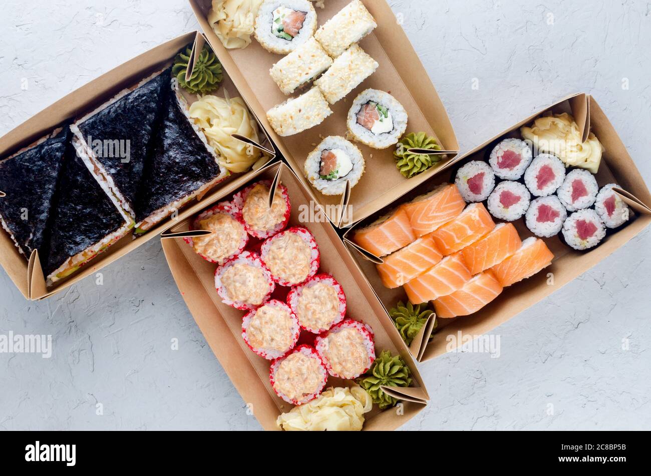 Leckere Sushi-Brötchen in Einweg-Kraftpapier-Boxen, Saucen, Essstäbchen. Sushi zum Mitnehmen oder Anliefern Stockfoto