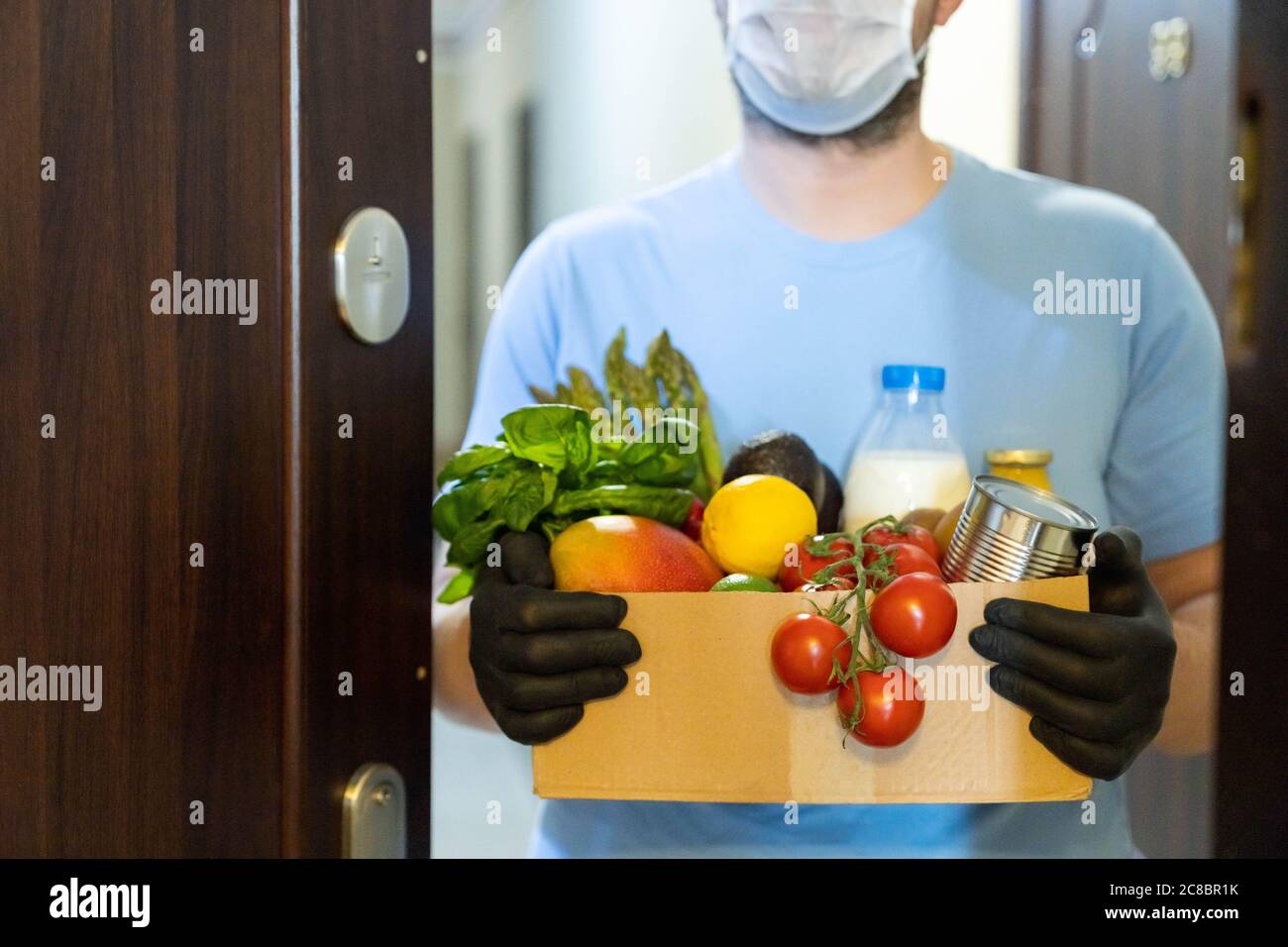 Konzept für sichere Lebensmittelzustellung - Lieferer hält Glocerien Stockfoto