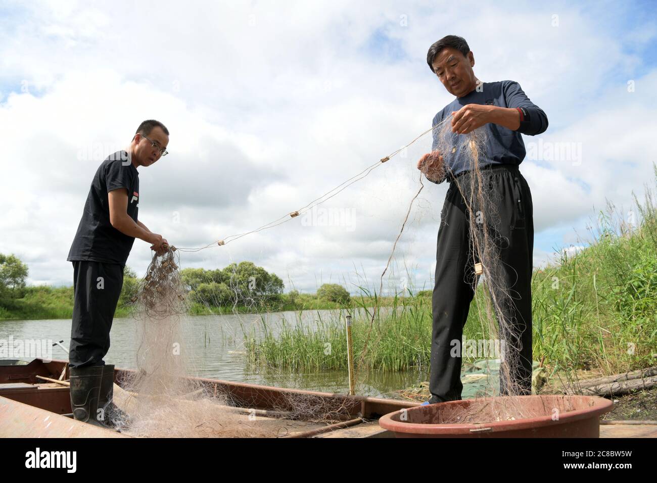 (200723) -- TONGJIANG, 23. Juli 2020 (Xinhua) -- die Fischzüchter Li Yanpeng (L) und sein Vater Li Jun sortieren Fischnetz im Dorf Bacha, Stadt Tongjiang, nordöstlich der Provinz Heilongjiang, 21. Juli 2020. Das Dorf Bacha, das von den Menschen der ethnischen Minderheit Hezhe dominiert wird, hat einen Weg der Armutsbekämpfung durch die Entwicklung einer Wirtschaft geführt, die den lokalen Bedingungen entspricht. Alle 14 registrierten armen Familien haben die Armut abgeschüttelt. Das verfügbare Pro-Kopf-Einkommen der Dorfbewohner wurde 22,150 von 16,102 Yuan (etwa 2,303 US-Dollar) im Jahr 2015 auf 3,168 Yuan (etwa 2019 US-Dollar) erhöht. (Xinhua/Wang Jianwei) Stockfoto