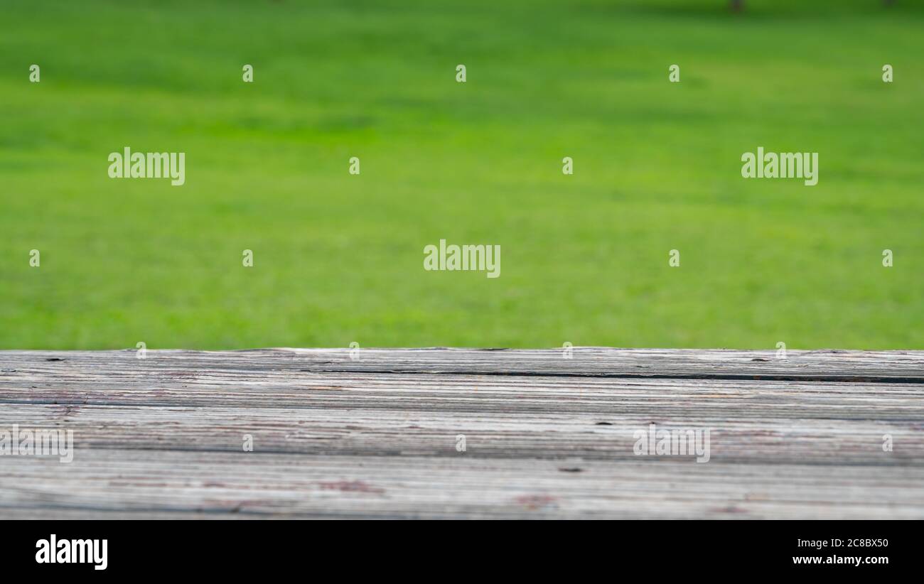 Holz Deck und verwischen Natur grünen Rasen Hintergrund. Stockfoto