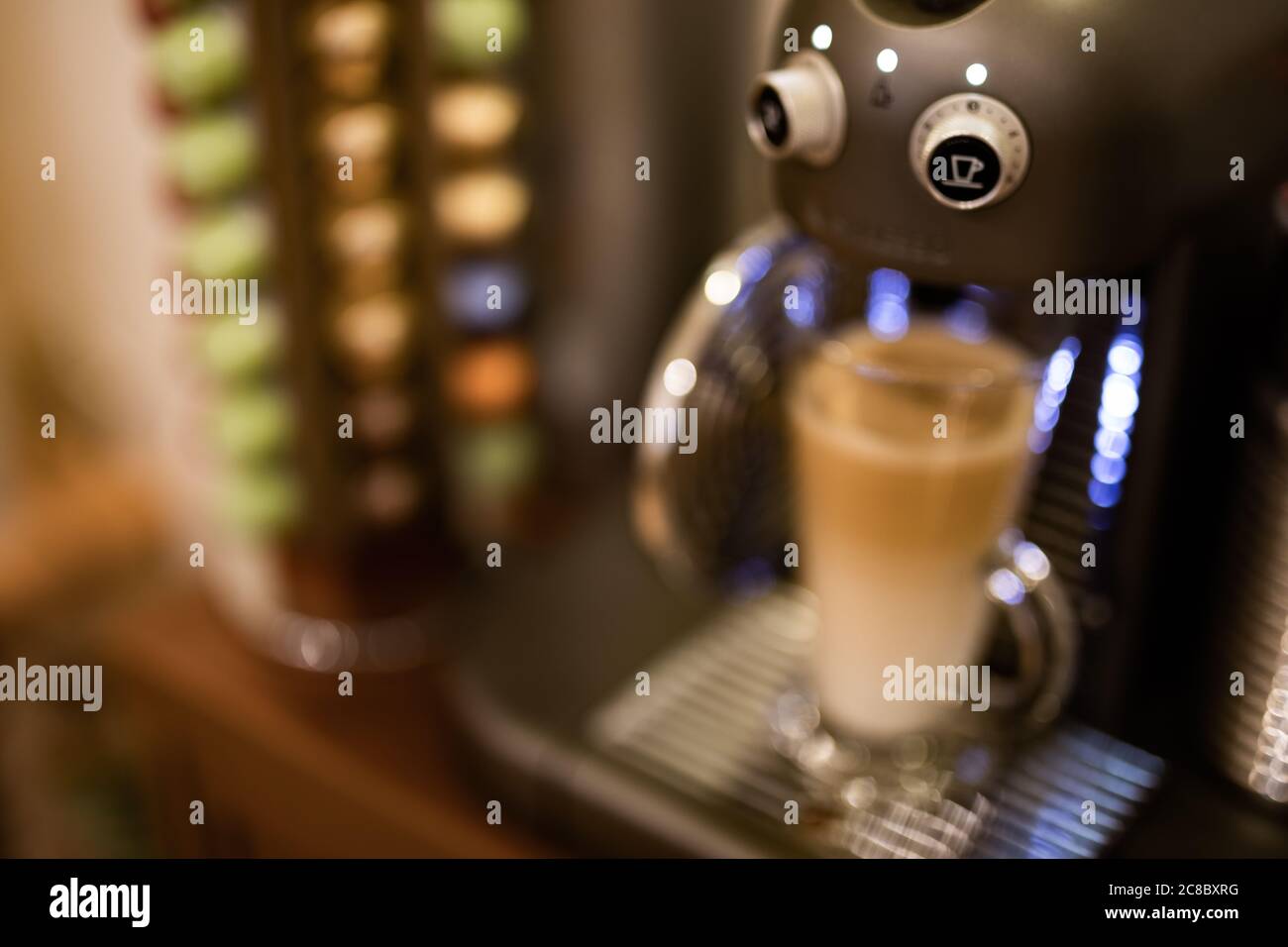 Latte Kaffee mit professioneller Maschine und verschwommene Kapseln Hintergrund Stockfoto