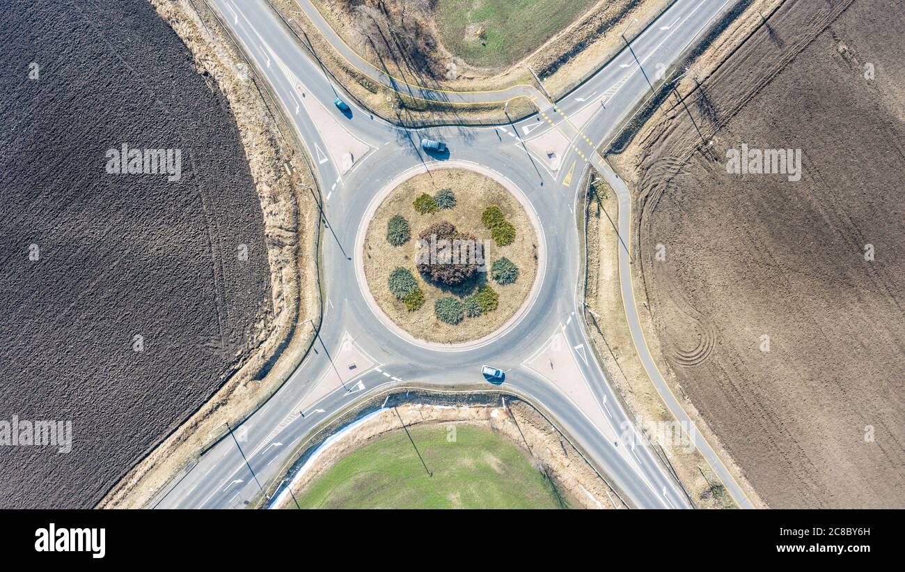 Luftaufnahme des Kreisel in der Landschaft mit ländlichen, landwirtschaftlichen Feldern. Kreisstraße: Europäischer Kreisverkehr um Agrarfeld mit wenig Verkehr Stockfoto
