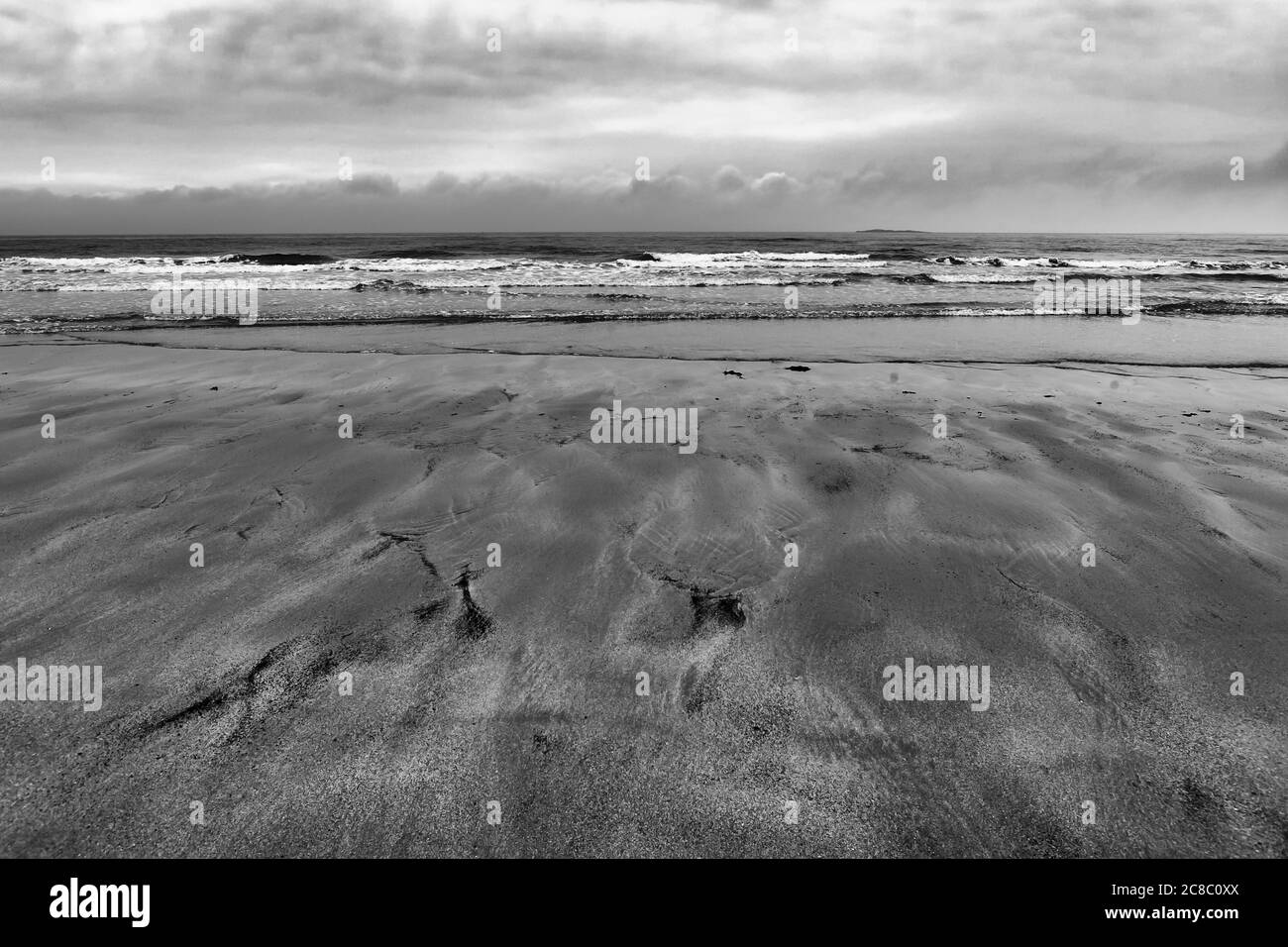 Die Nordsee und die Insel Inner Farne von Bamburgh Sands, Northumberland, England, Großbritannien bei Ebbe, an einem trüben, bewölkten Tag. Schwarz-Weiß-Version Stockfoto