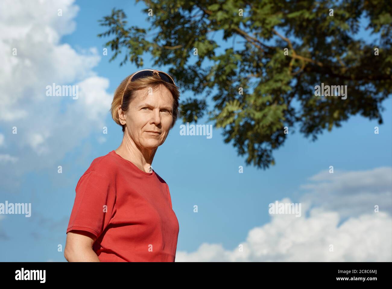 Porträt einer Frau mittleren Alters in einem roten T-Shirt bei schönem Wetter, draußen. Stockfoto