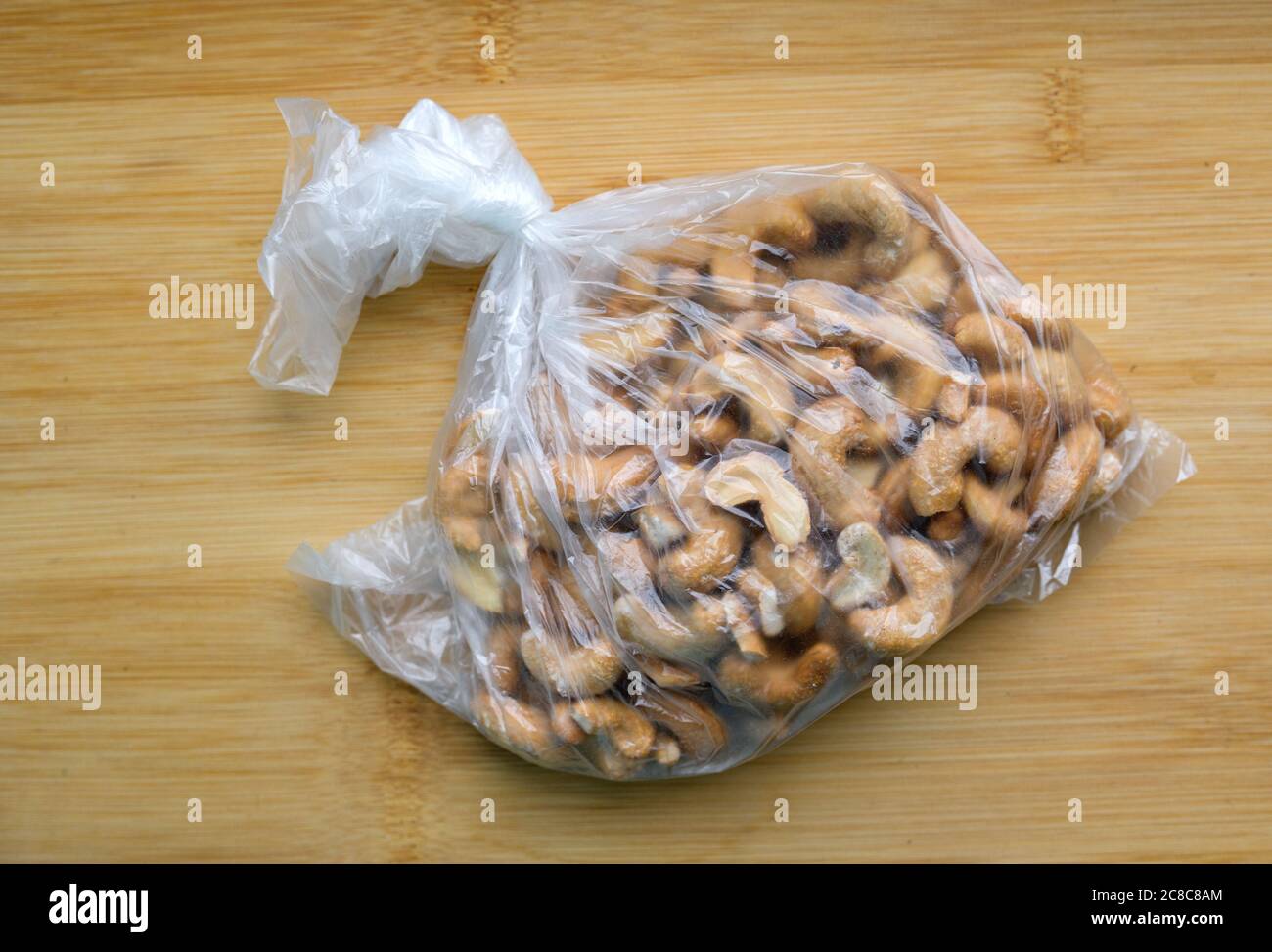 Cashewnüsse in einem Plastikbeutel auf Holztisch. Stockfoto