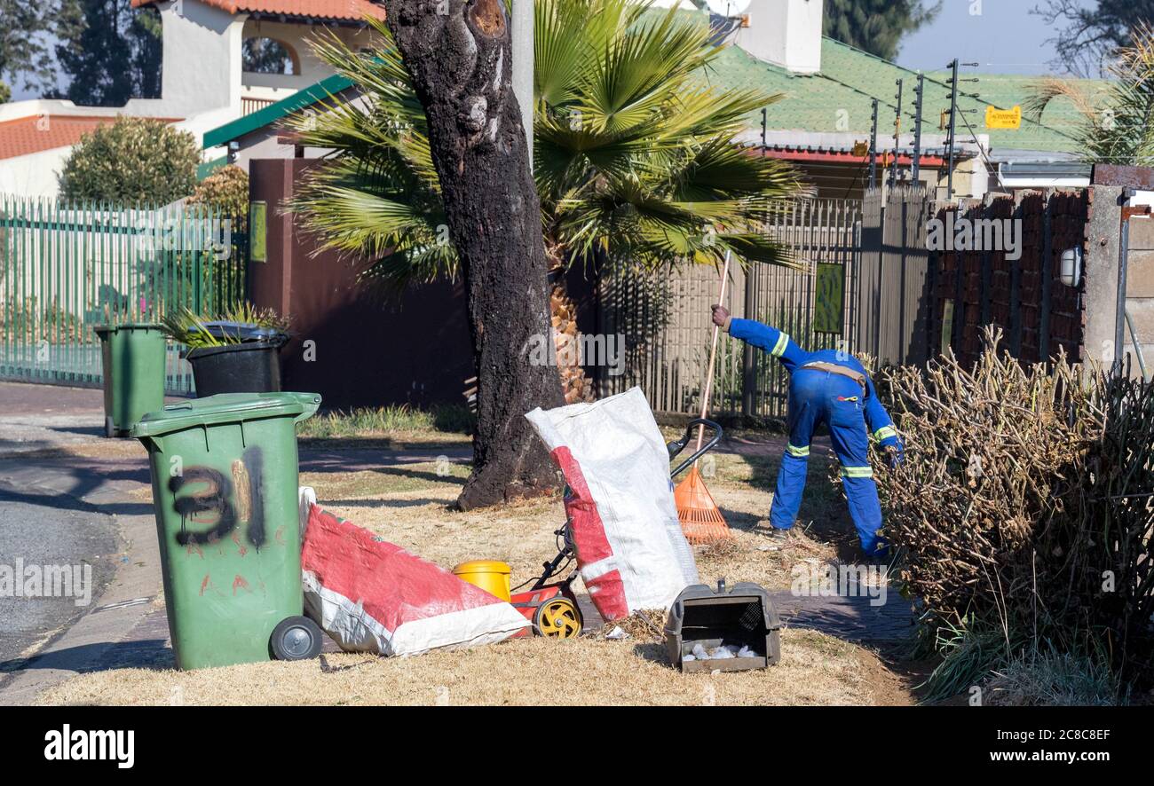 Alberton, Südafrika - nicht identifizierte schwarze Männer arbeiten als Gelegenheitsarbeiter, die Gartenarbeit in einem Wohngarten leisten Stockfoto