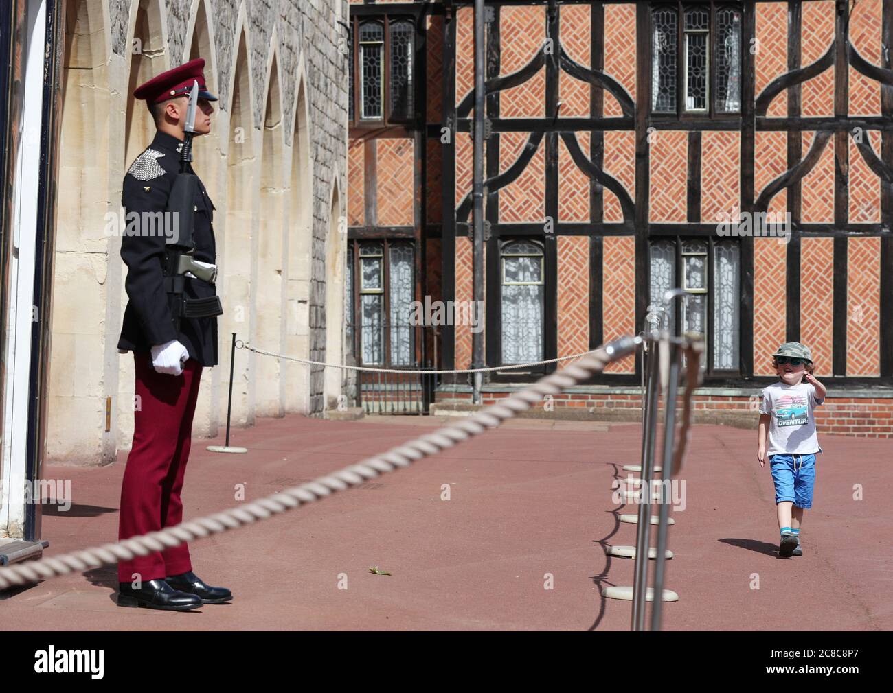 Ein junger Besucher imitiert den marsch eines Wachmanns aus den königlichen Hussaren der Königin im Schloss Windsor, der nach Aufhebung weiterer Beschränkungen für die Sperrung des Coronavirus in England wieder für die Öffentlichkeit zugänglich gemacht wurde. Stockfoto