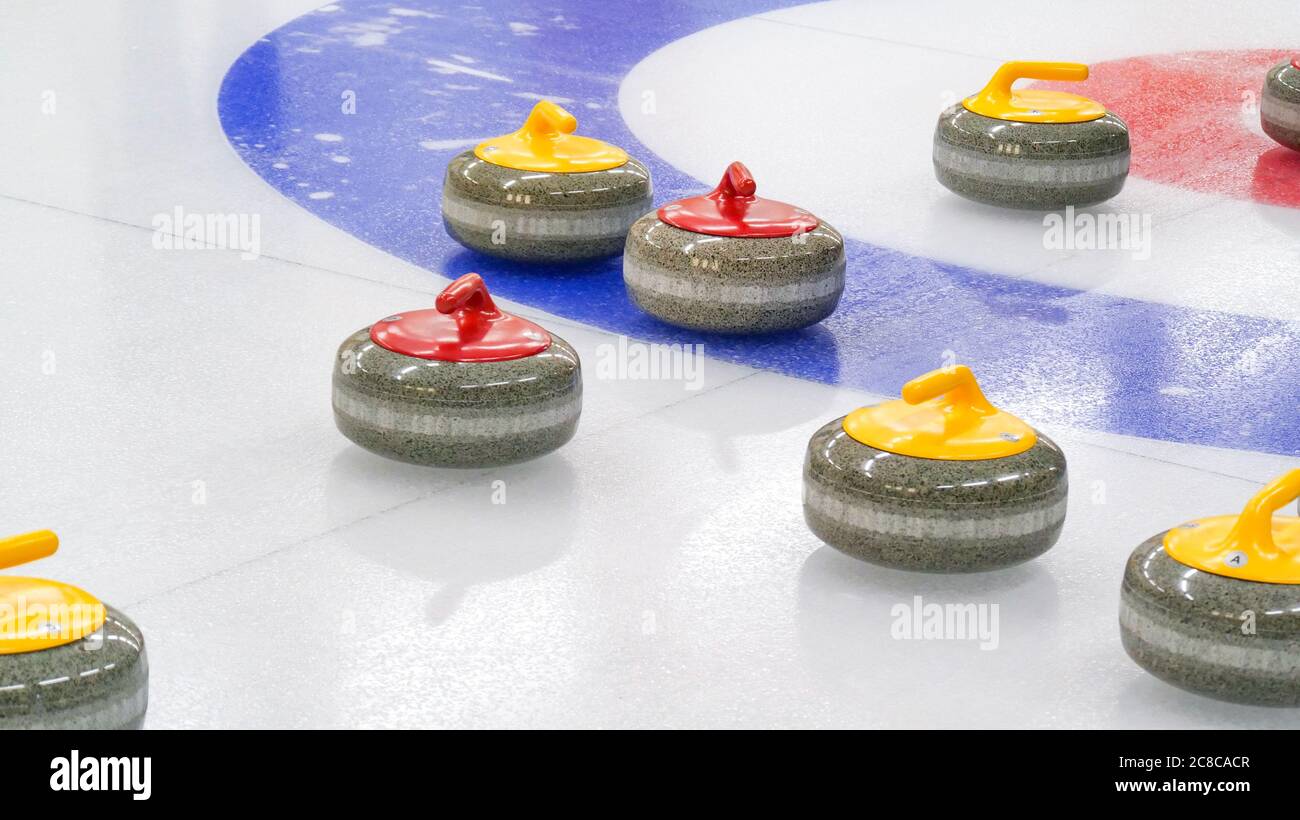 Curling ist ein Winterteam olympischen Sport. Eisstockschießen Granitsteine auf Eisstockblech mit rotem und blauem Kreis und sichtbaren Kieselsteinen. Innenbahn. Stockfoto