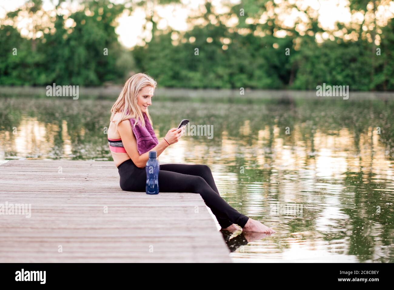 Sportler mit Smartphone nach dem Training - kaukasische fit Frau in Sportbekleidung mit einem Handy Stockfoto