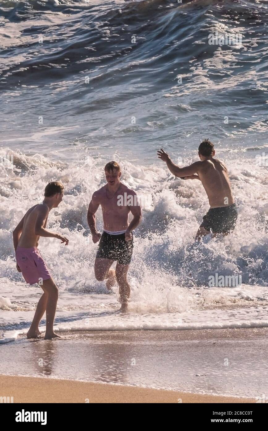 Männliche Urlauber laufen im Meer am Fistral Beach in Newquay in Cornwall. Stockfoto