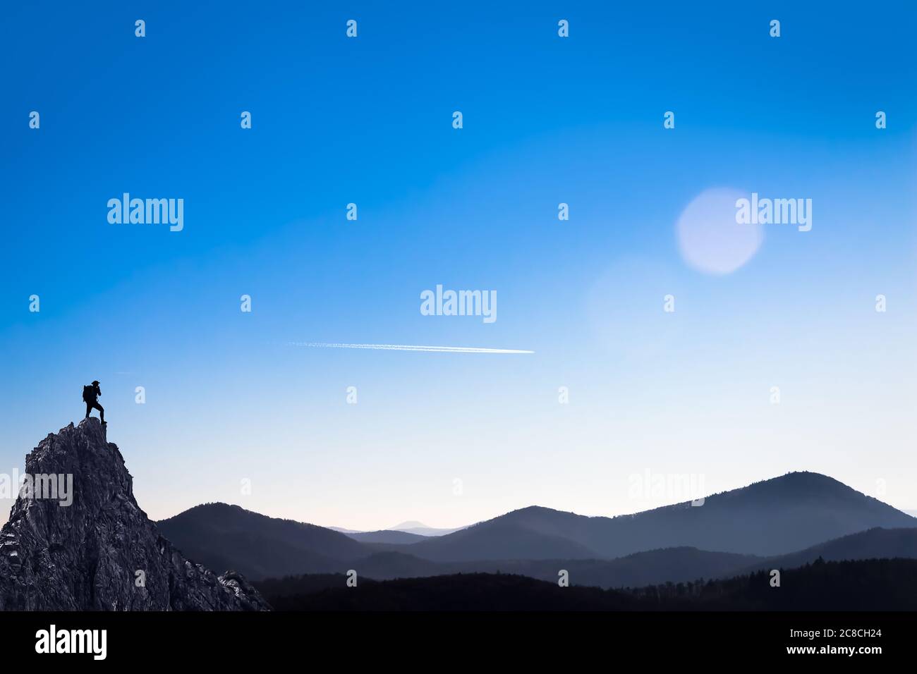 Wanderer auf dem Gipfel eines Berges mit Blick auf eine hügelige Landschaft Stockfoto