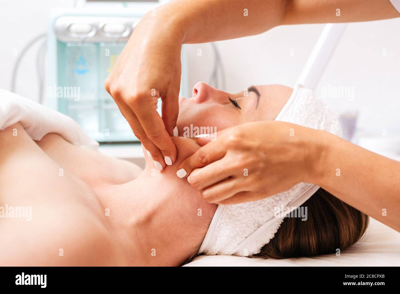 Der Kosmetiker gibt dem Kunden eine Gesichtsmassage. Seitenansicht und Nahaufnahme. Konzept der Kosmetologie und Behandlung. Stockfoto