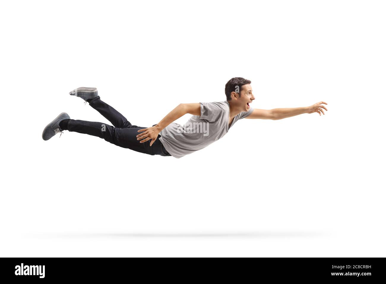 In voller Länge Profilaufnahme eines lässigen jungen Mannes, der fliegt und nach etwas isoliert auf weißem Hintergrund greift Stockfoto