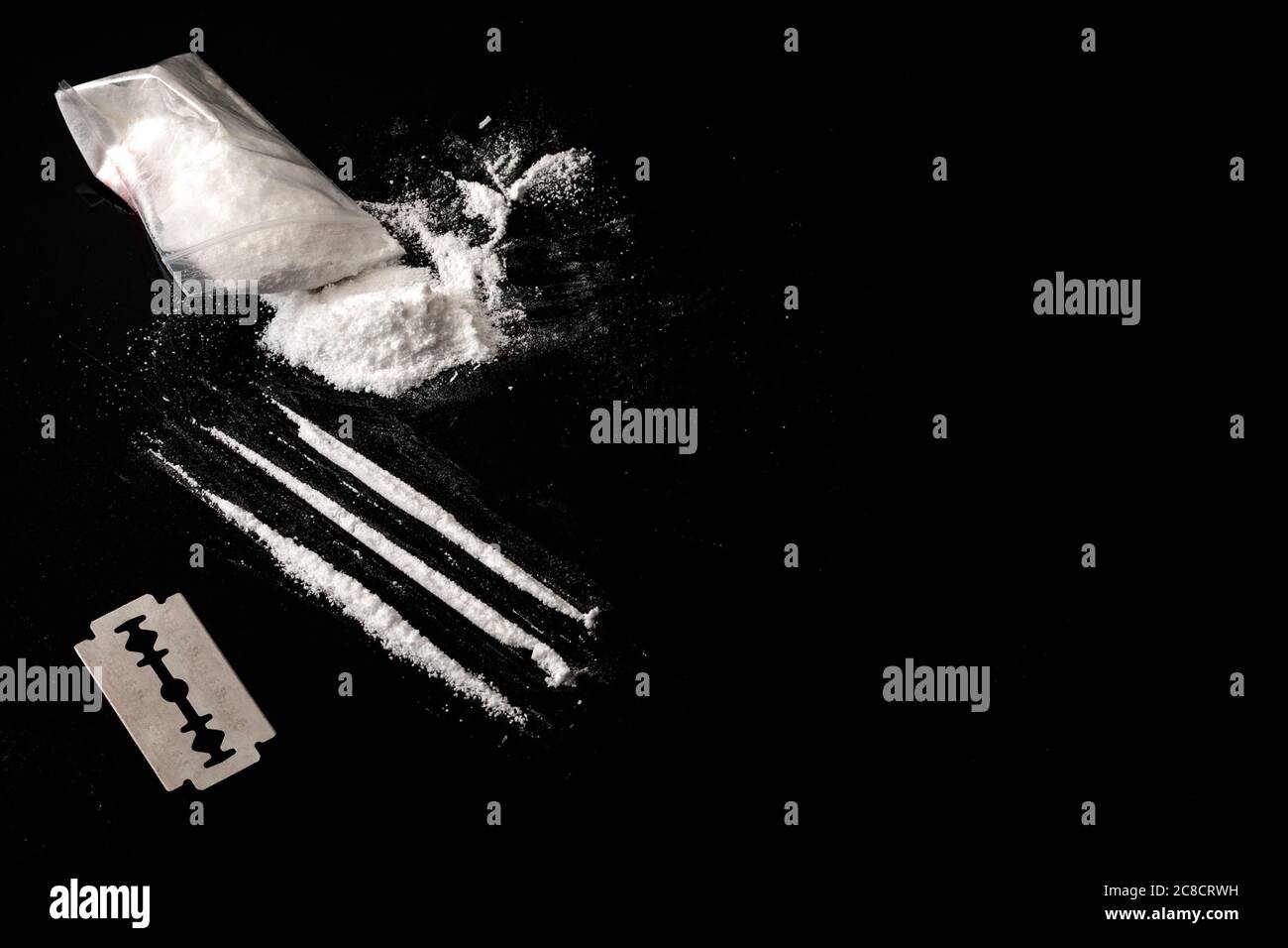 Drogenabhängigkeit und Drogenmissbrauch Konzept Thema mit Linien von Kokain, eine kleine Tasche mit weißem Pulver und eine Klinge verwendet, um jede Zeile von Betäubungsmitteln zu schneiden o Stockfoto