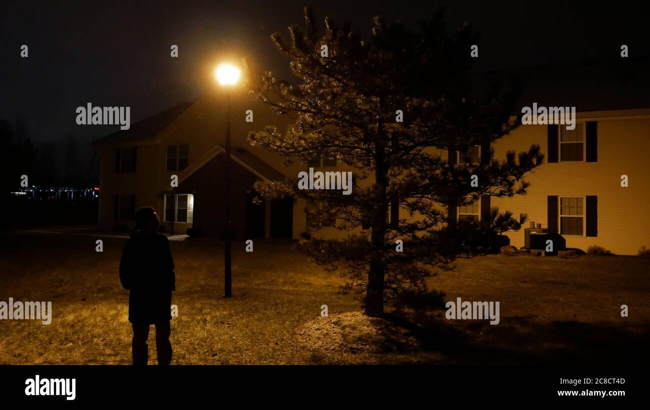 Mann unter Baum stehend, beleuchtet von Straßenbeleuchtung Stockfoto