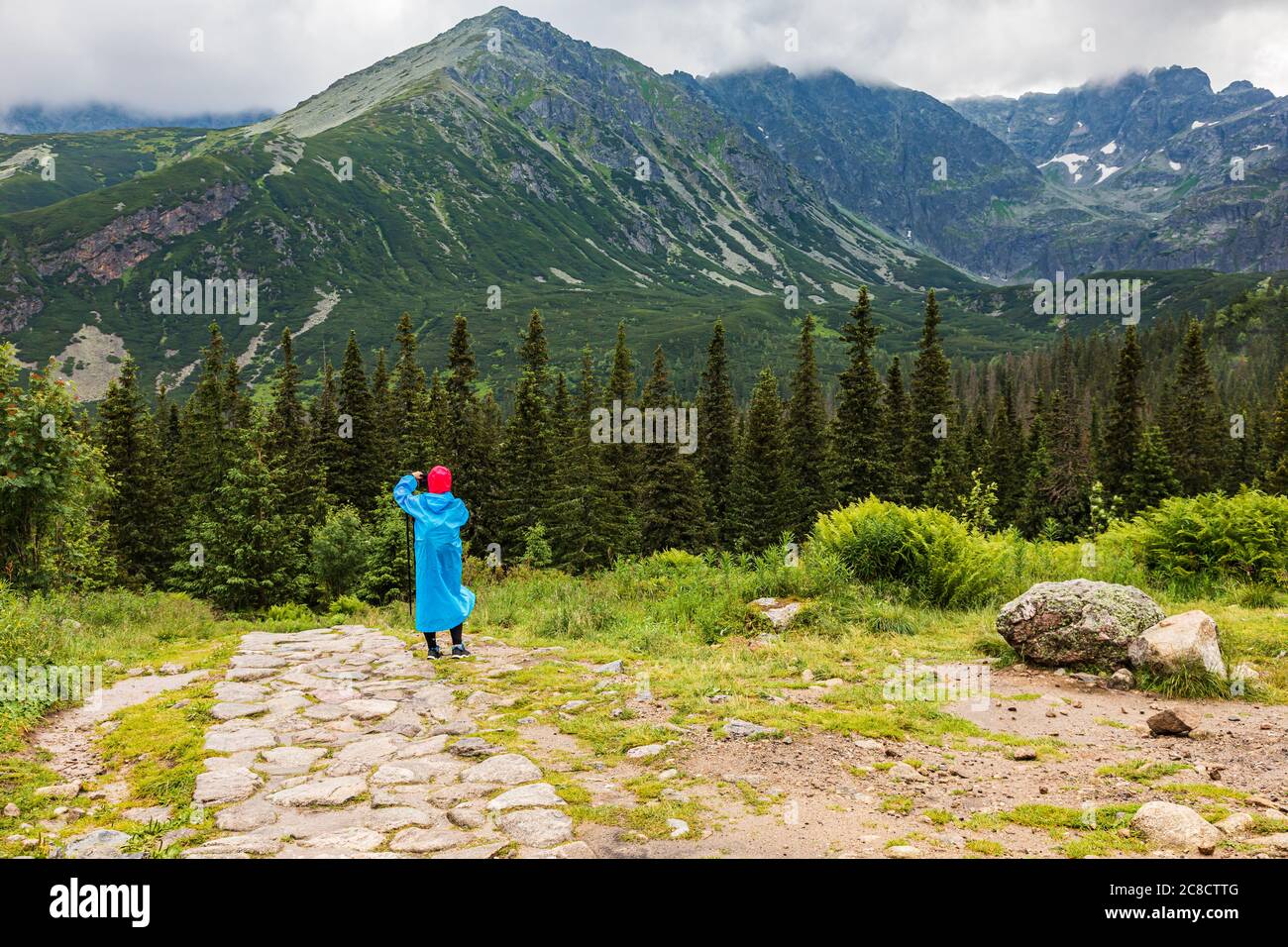 Hikker in einem blauen Plastikregenmantel, der bei schlechtem Wetter in der Tatra fotografiert Stockfoto