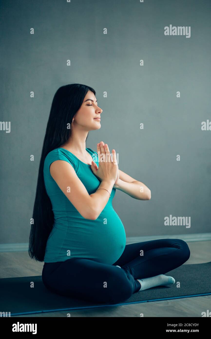 Schwangerschaftsyoga. Junge schwangere Frau macht Yoga zu Hause. Stockfoto