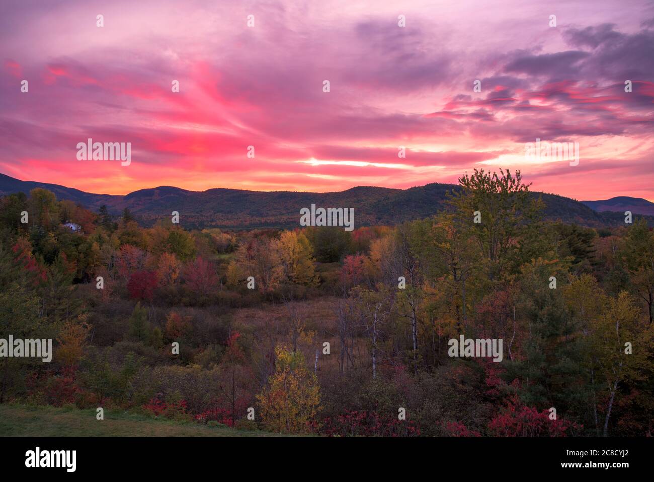 Atemberaubender Sonnenuntergang über bewaldeten Bergen auf dem Gipfel des Herbstlaubes Stockfoto