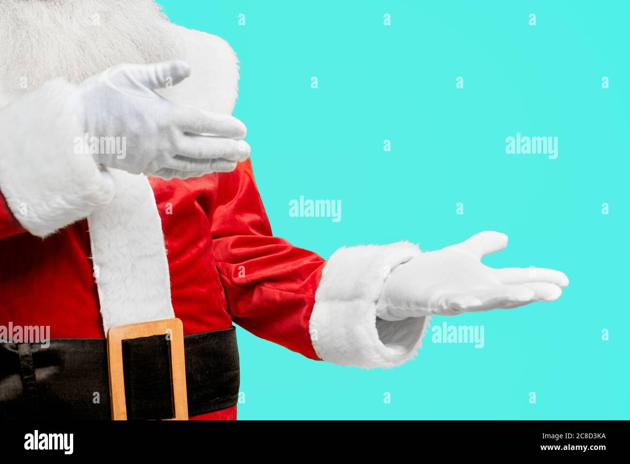 Vorderansicht von Inkognito mit langem weißen Bart in rotem Weihnachtsmann Kostüm. Isolierte Ernte von Mann in weißen Handschuhen zeigt auf leeren Raum auf blauen Studio-Hintergrund. Konzept der Werbung. Stockfoto