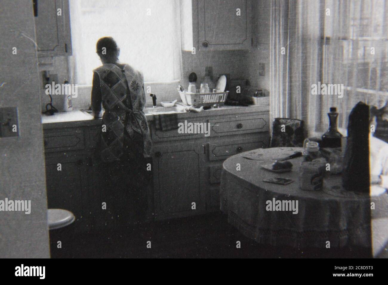 Feine 70er Jahre Vintage schwarz-weiß Lifestyle-Fotografie einer Frau, die ihre täglichen Aufgaben an der Küchenspüle. Stockfoto