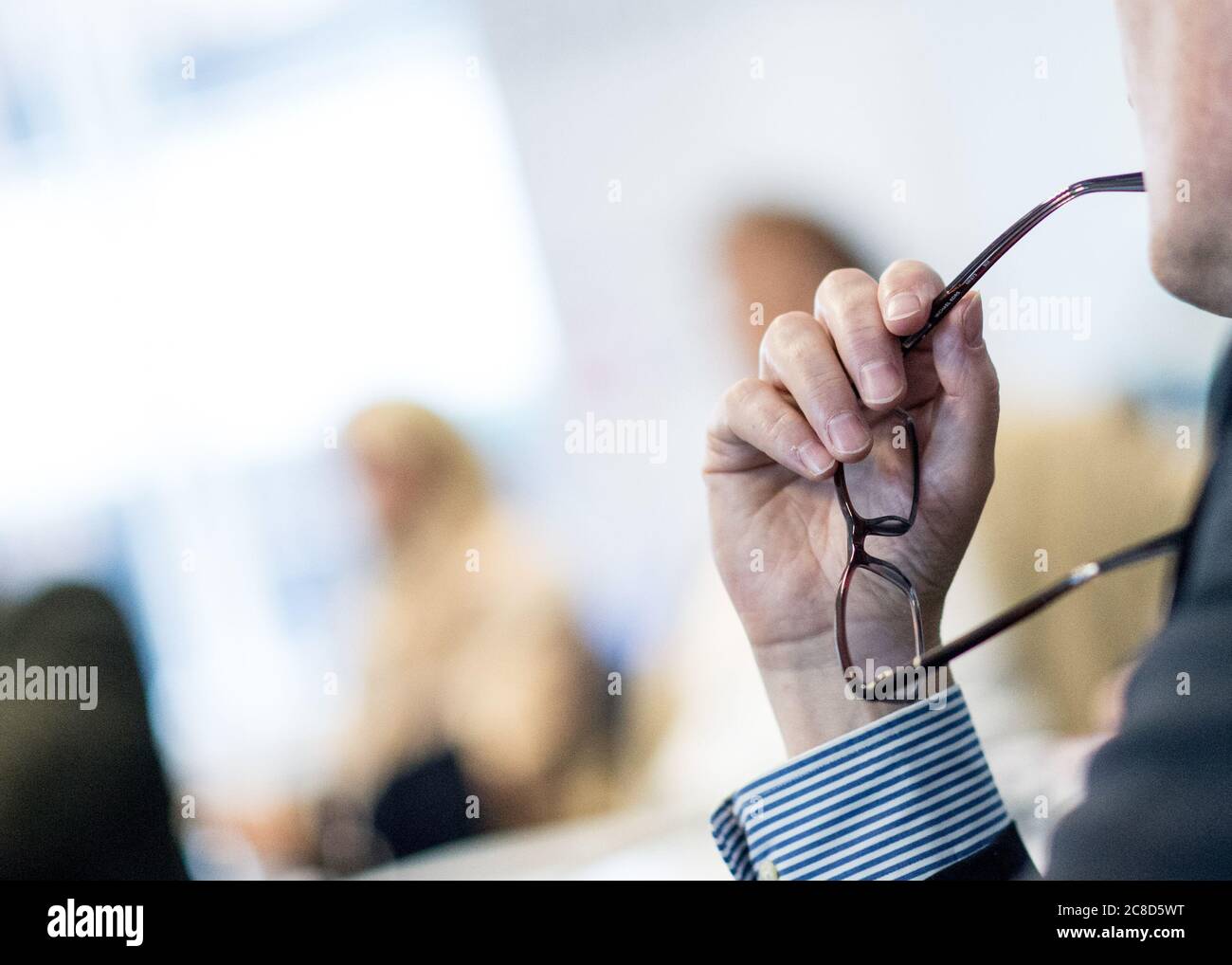 Geschäftsmann hält Brillen Hören bei EINEM Geschäftstreffen Stockfoto