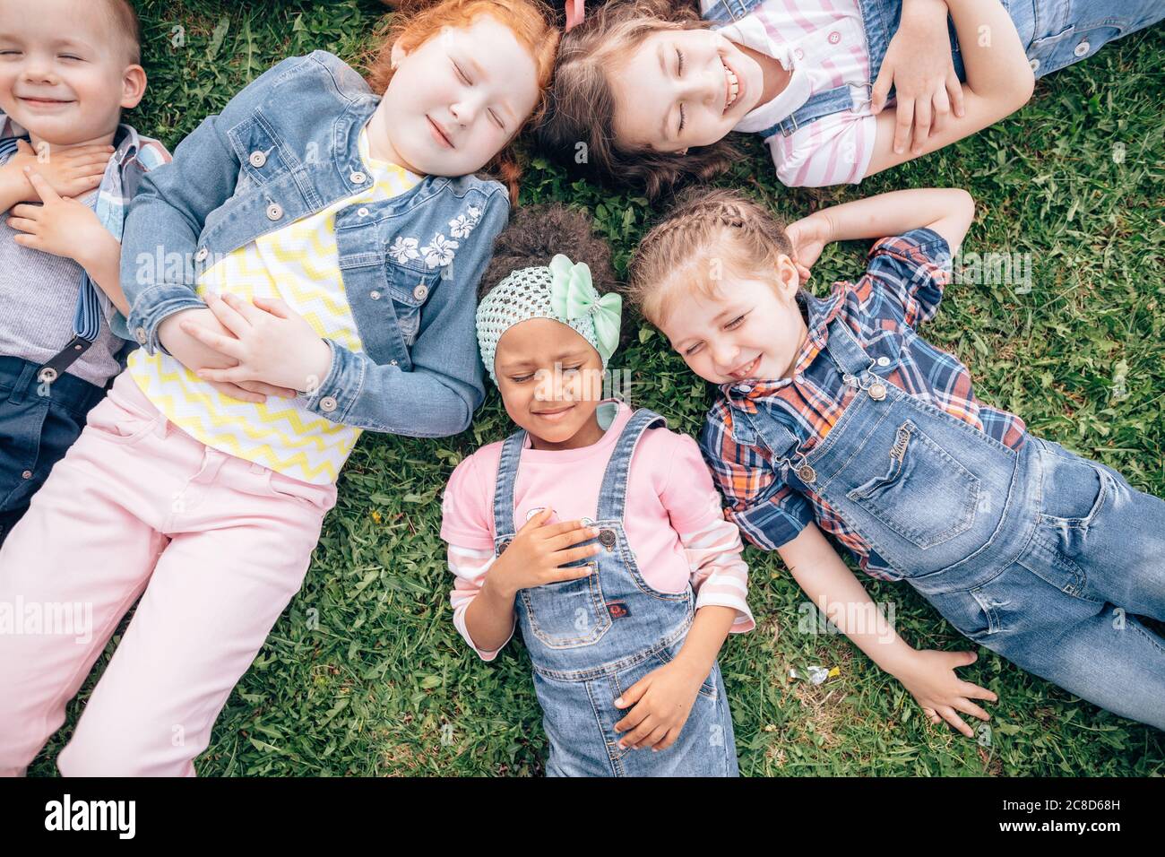 Multikulturelle Gruppe von Mädchen auf dem Gras. Im Freien. Das Konzept einer glücklichen Kindheit und eine Mädchenfreundschaft Stockfoto