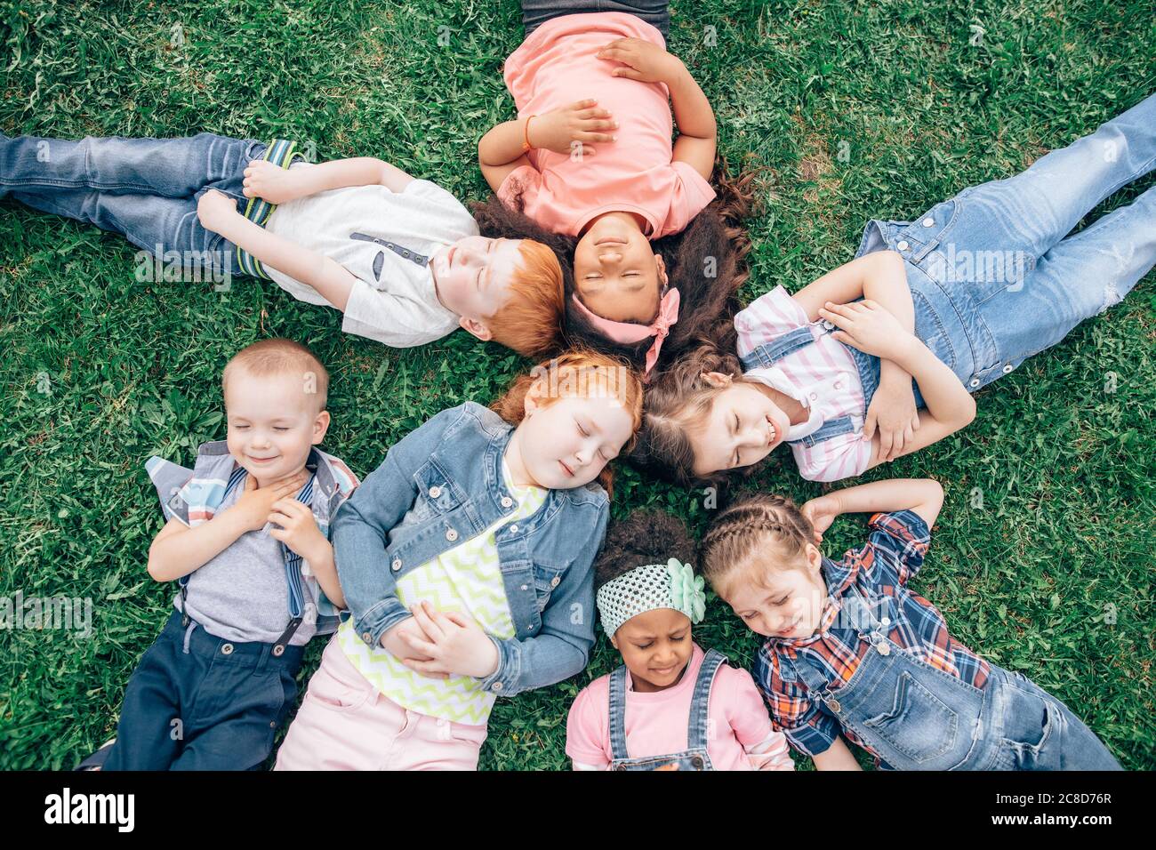 Multikulturelle Gruppe von Mädchen auf dem Gras. Im Freien. Das Konzept einer glücklichen Kindheit und eine Mädchenfreundschaft Stockfoto