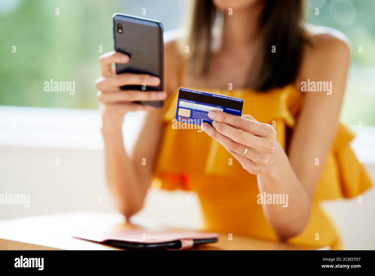 Frau, die auf ihr Telefon und ihre Kreditkarte schaut Stockfoto