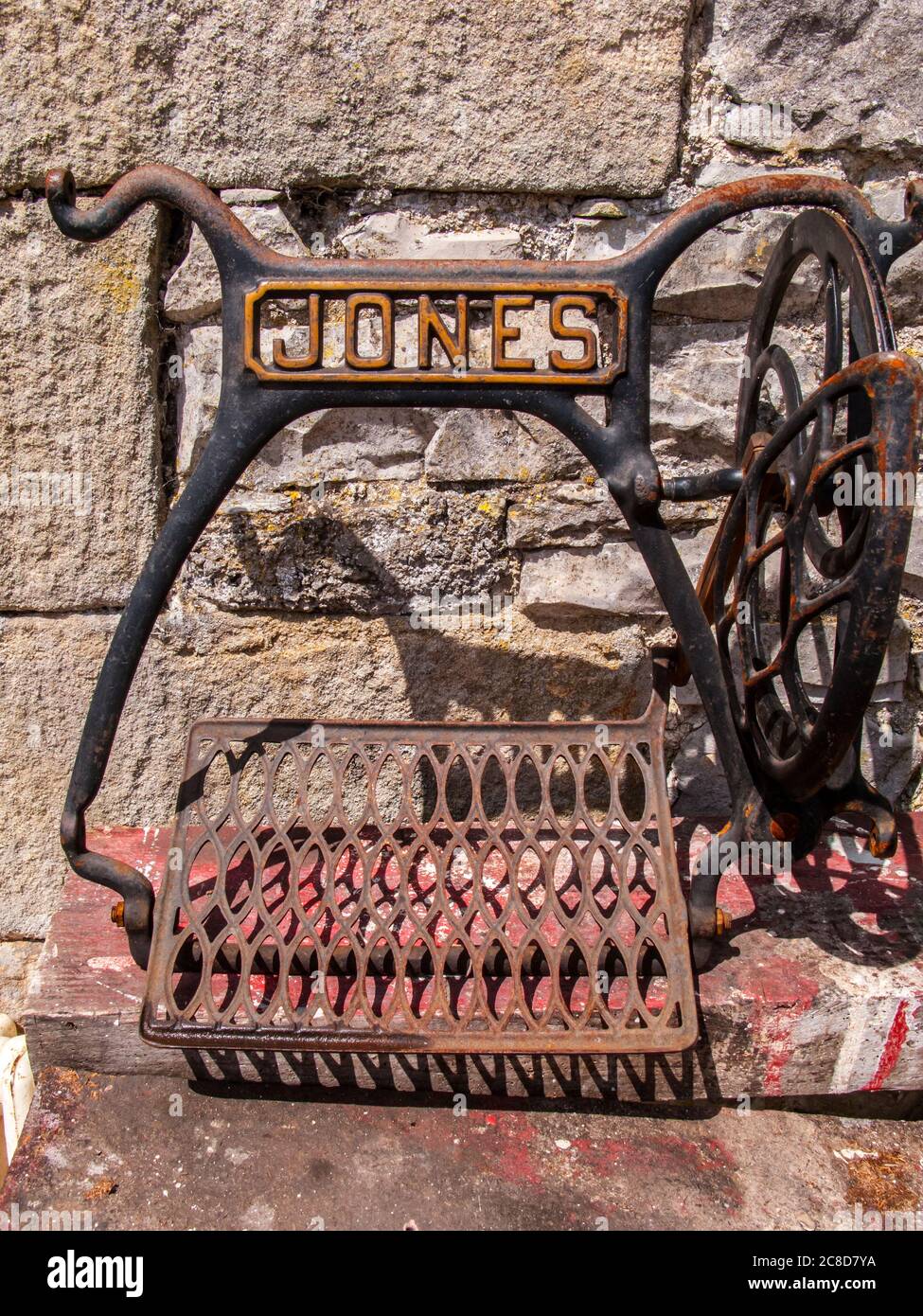 Reste der Antique Jones Tretnähmaschine gegen Steinwand Stockfoto