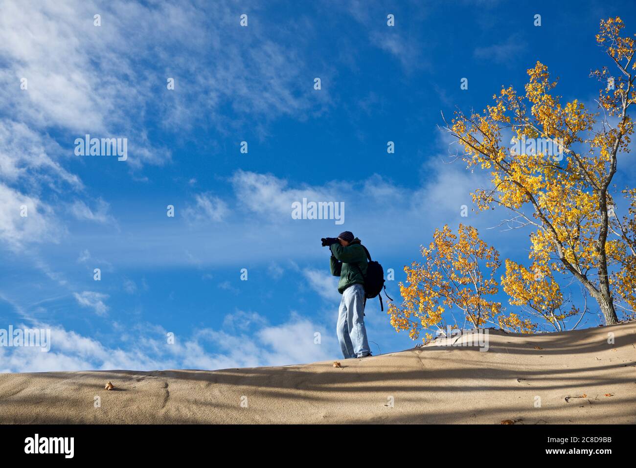 Fotograf in der Sanddüne mit blauem Himmel und Herbstlaub Farbe Stockfoto