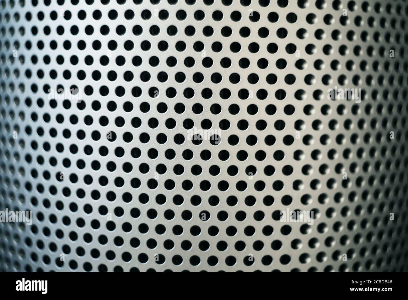 Abstrakte Abbildung einer silbrig geschwungenen Metalloberfläche mit vielen kleinen runden Löchern. Filter. Stockfoto
