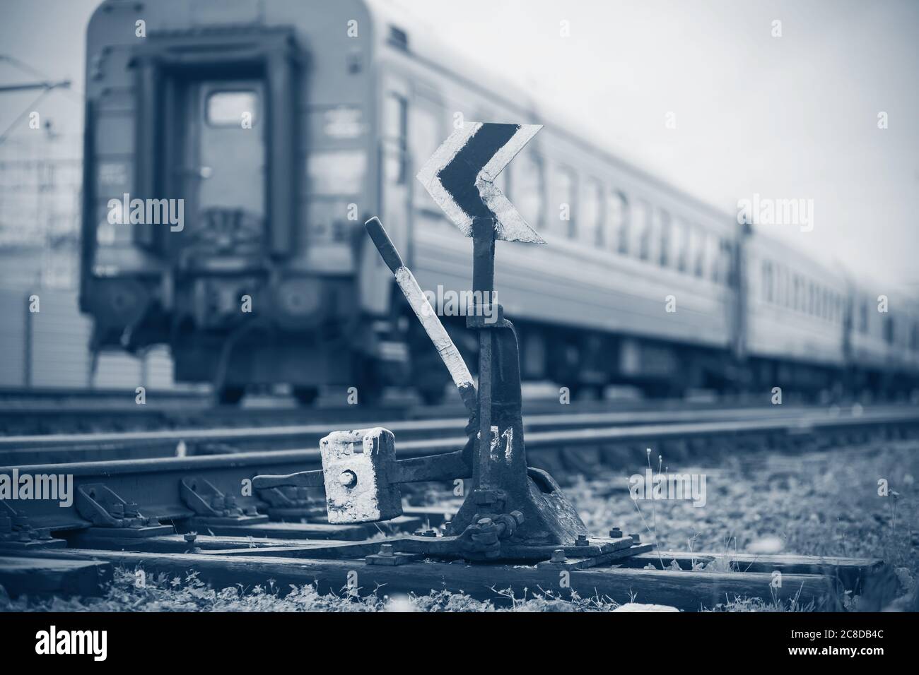 Trauriges monochromes Bild eines abfahrenden Zuges, der an der alten Eisenbahnschalte vorbeifährt. Melancholie. Nostalgie Stockfoto