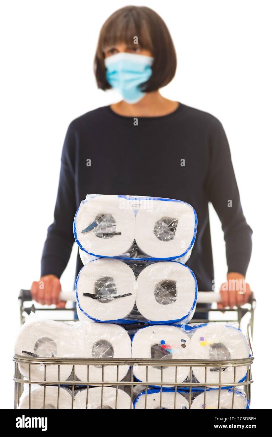 Frau trägt chirurgische Maske schieben Supermarkt Einkaufswagen mit Toilettenrolle geladen. Stockfoto