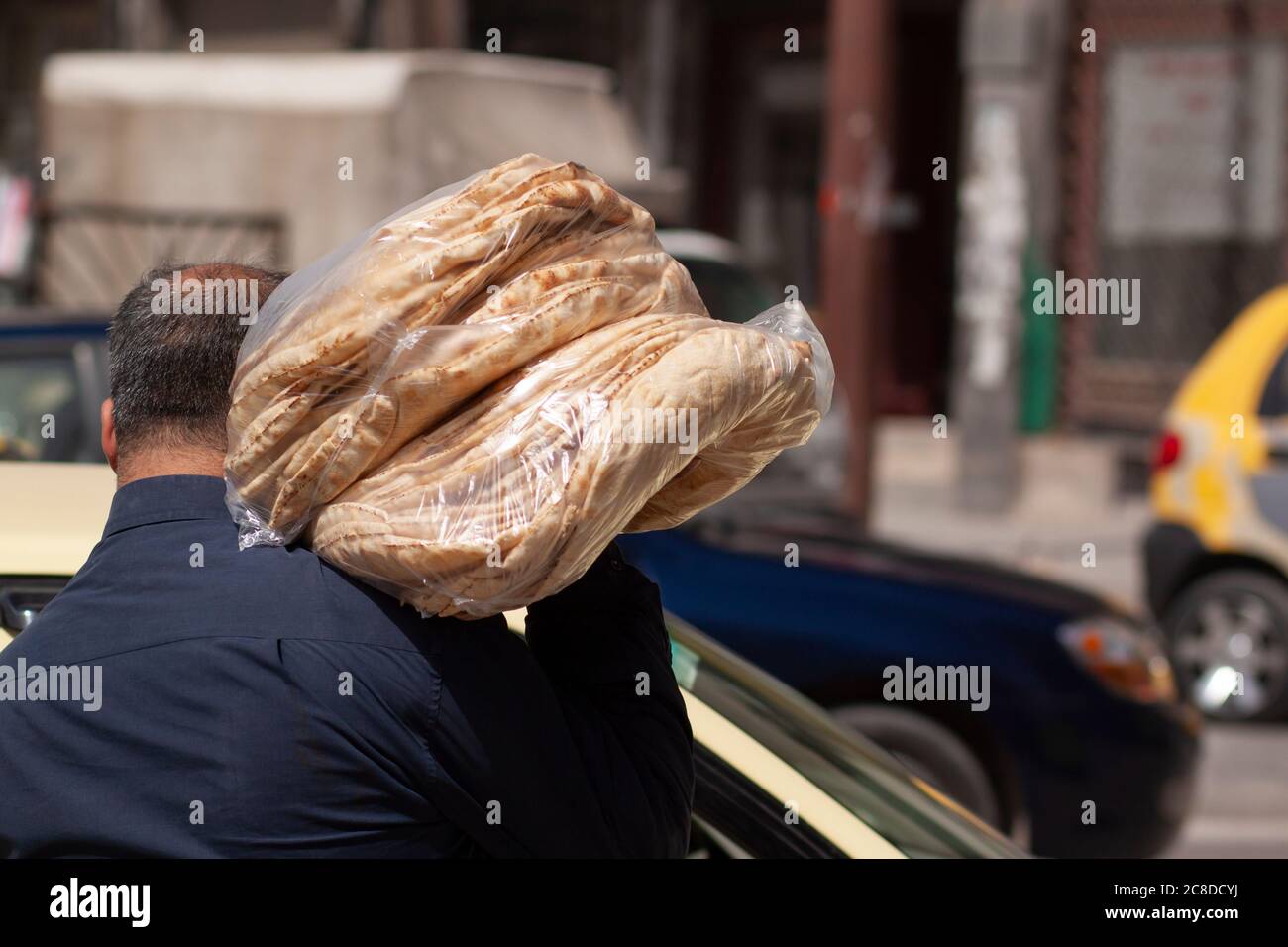 Ein syrischer Bäcker trägt frisch zubereitetes traditionelles Fladenbrot auf der Straße. Die Brote werden gestapelt und in Plastiktüten gelegt. Er legte die Taschen auf Stockfoto