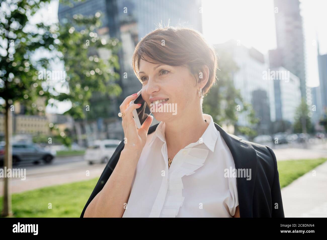 Nahaufnahme einer Geschäftsfrau mit kurzen Haaren, die über ein Smartphone spricht In der Stadt Stockfoto