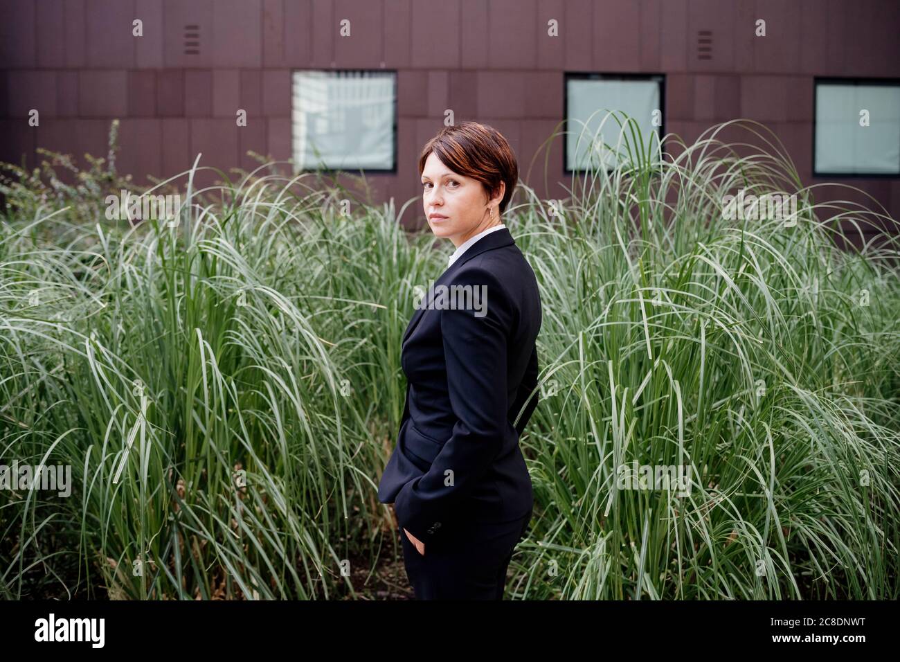 Geschäftsfrau mit kurzen Haaren steht bei Pflanzen in der Stadt Stockfoto