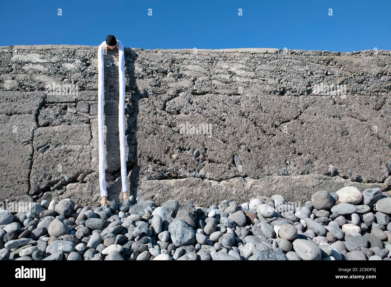 Frau mit künstlichen langen Händen Biegen über Haltewand an Strand Stockfoto