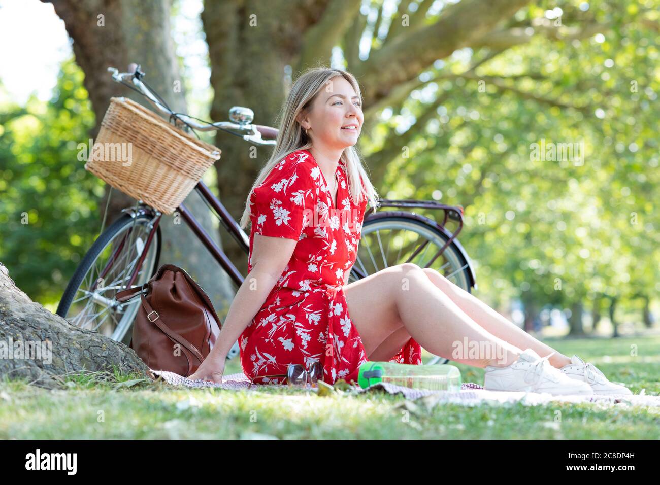 Nachdenkliche Frau, die im öffentlichen Park sitzt Stockfoto