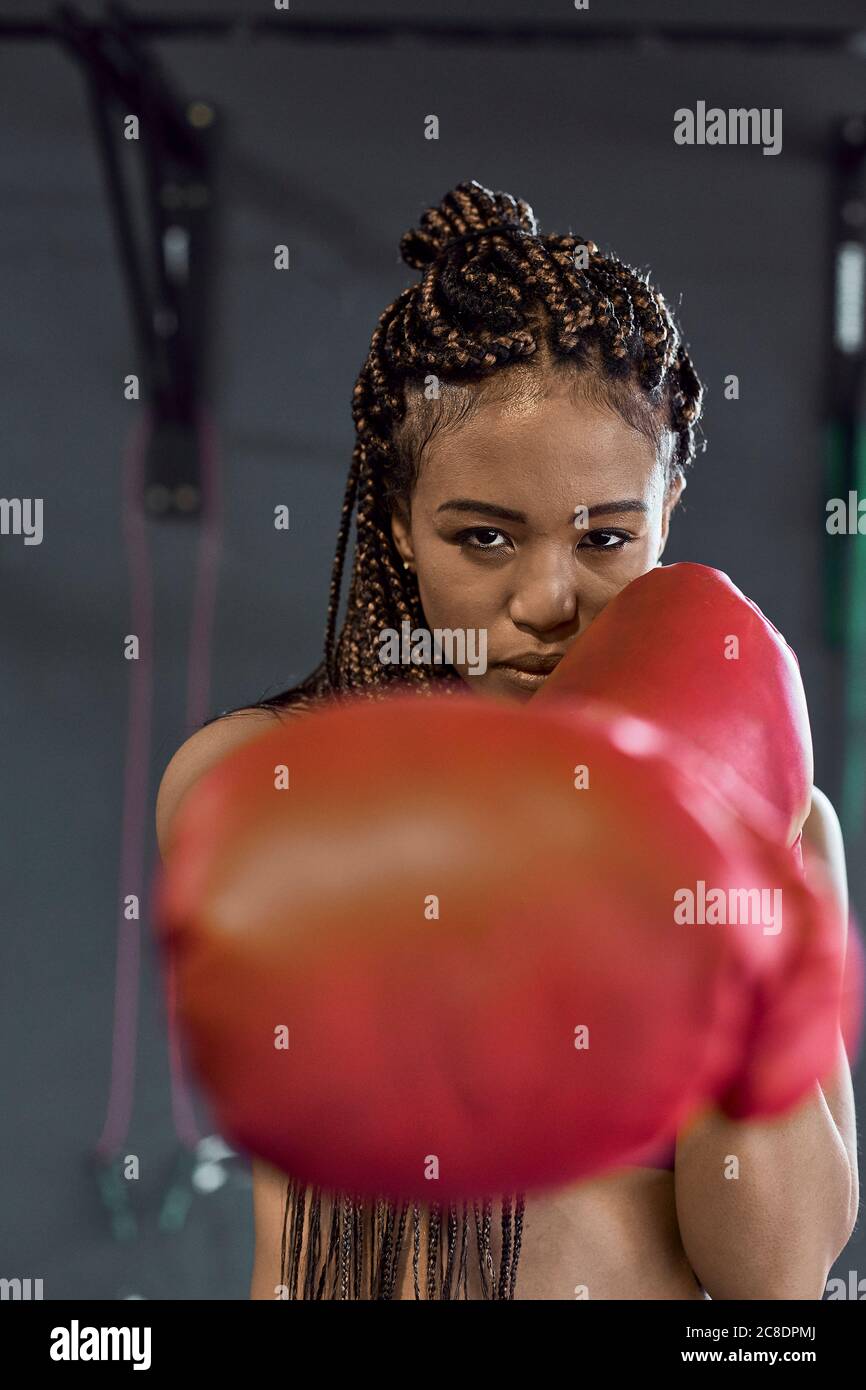 Selbstbewusste junge Frau trägt rote Boxhandschuhe Training im Fitnessstudio Stockfoto
