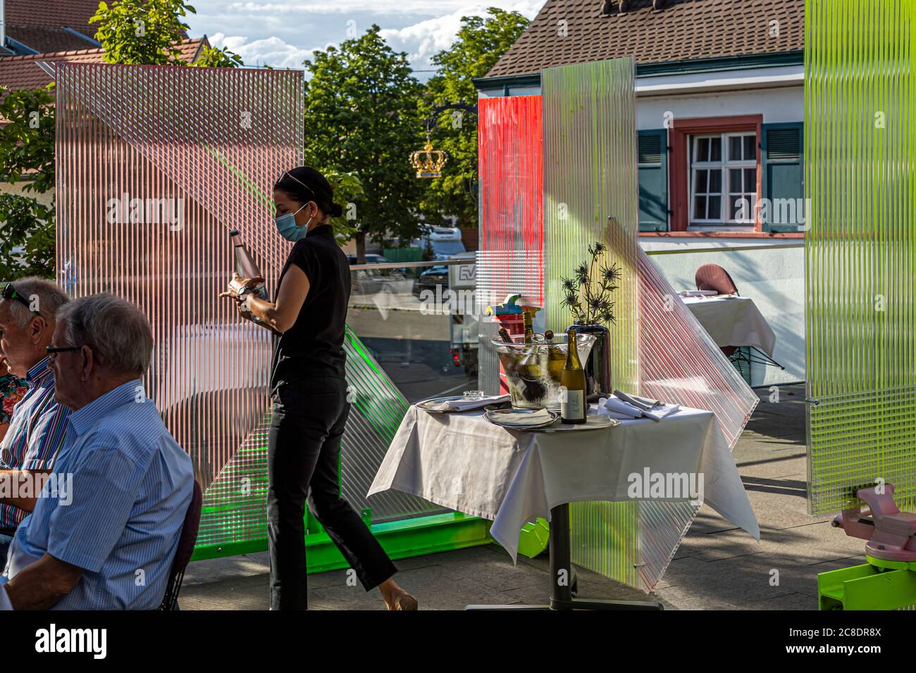 Außengastronomie mit künstlerisch gestalteten Trennwänden und Kellner mit Schutzmasken im Hotel Krone in weil am Rhein, Deutschland Stockfoto