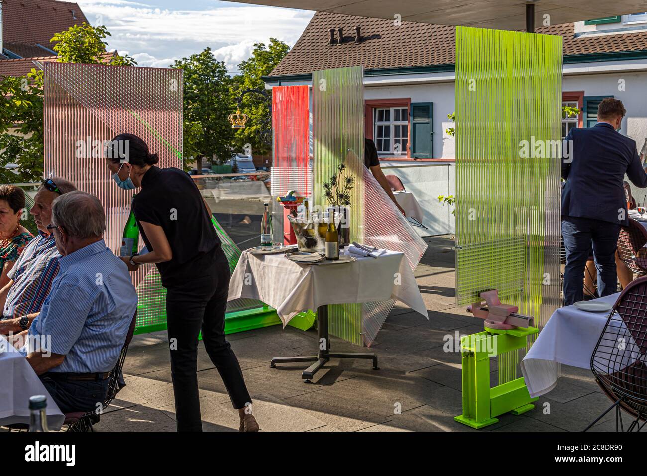 Außengastronomie mit künstlerisch gestalteten Trennwänden und Kellner mit Schutzmasken im Hotel Krone in weil am Rhein, Deutschland Stockfoto