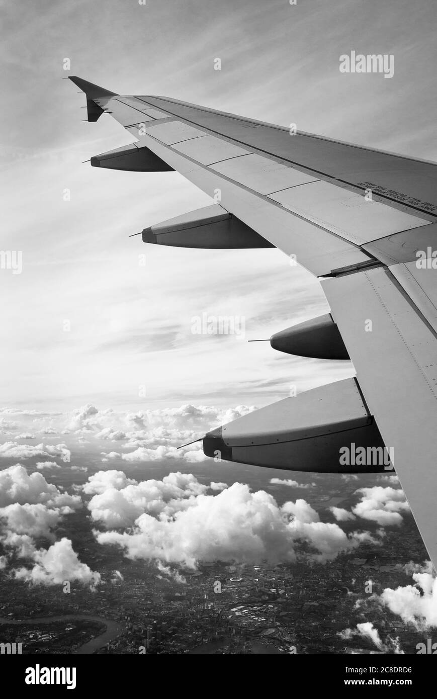 Hafenflügel eines zivilen Verkehrsflugzeugs, das auf dem Weg zu einem ausländischen Ziel fliegt. Beachten Sie die Steuerflächen, die als Klappen bezeichnet werden, um den Kurswechsel im Flug zu erleichtern Stockfoto